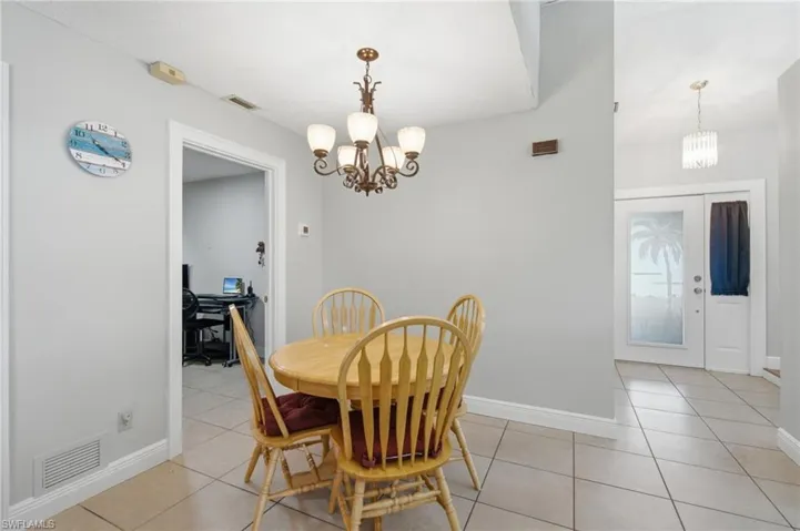 Tile flooring extending through an open doorway, featuring a ceiling-mounted chandelier