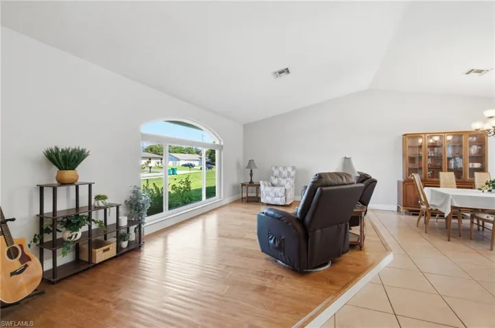Living area featuring vaulted ceilings, wood-finish flooring, and an arched picture window