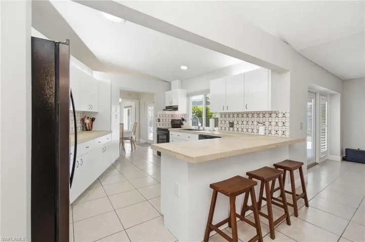 Bright kitchen featuring white cabinetry, light-toned countertops, and a patterned tile backsplash