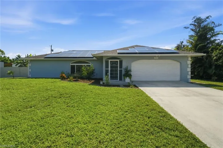 Single-story residence featuring a two-car garage, concrete driveway, and a shingled roof with visible solar panels