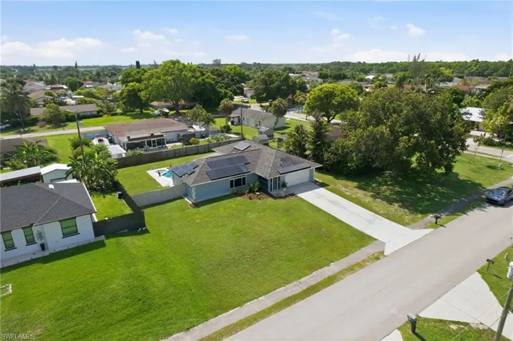 Single-story residence featuring an attached garage, a paved driveway, and solar panels on the roof