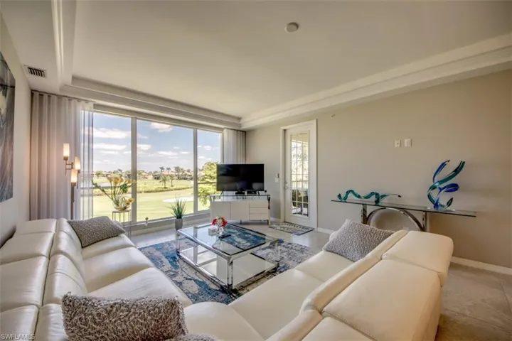 Tiled living area featuring a tray ceiling, baseboards, and visible vents