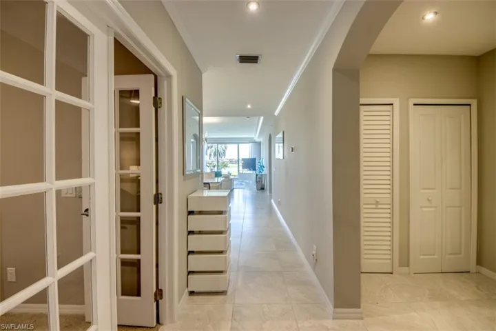 Hall featuring visible vents, baseboards, arched walkways, and light tile patterned floors