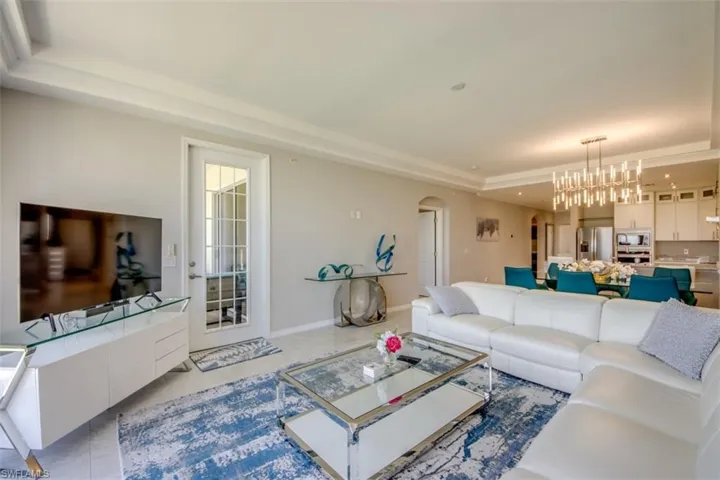 Living room featuring a raised ceiling, arched walkways, and an inviting chandelier