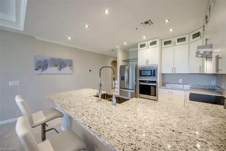 Kitchen featuring visible vents, exhaust hood, a sink, ornamental molding, and appliances with stainless steel finishes