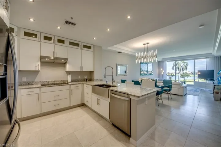 Kitchen featuring fridge with ice dispenser, under cabinet range hood, dishwasher, a sink, and black electric stovetop