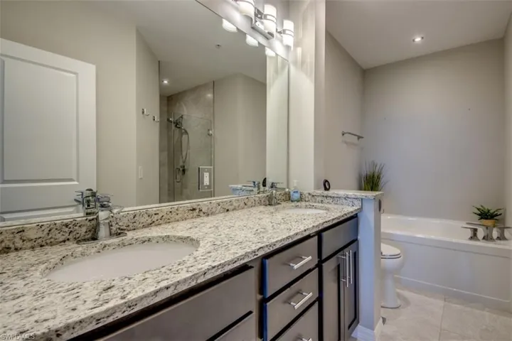 Full bath featuring a garden tub, a sink, a stall shower, double vanity, and tile patterned floors