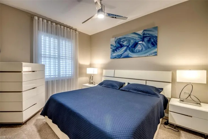 Bedroom with light colored carpet and a ceiling fan