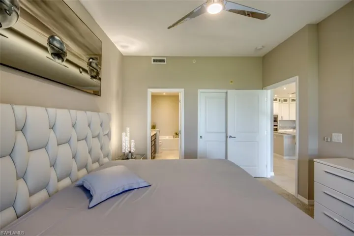 Bedroom with connected bathroom, a ceiling fan, visible vents, light carpet, and baseboards