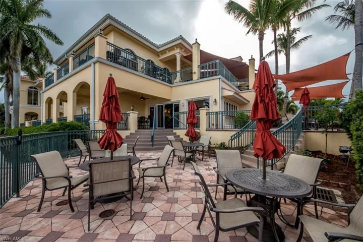 View of patio featuring outdoor dining area, a balcony, and fence
