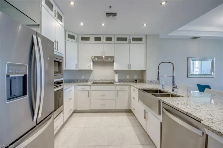 Kitchen featuring a sink, white cabinets, appliances with stainless steel finishes, and under cabinet range hood