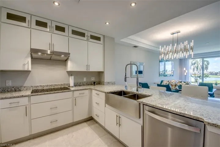 Kitchen featuring white cabinets, under cabinet range hood, black electric cooktop, stainless steel dishwasher, and a sink