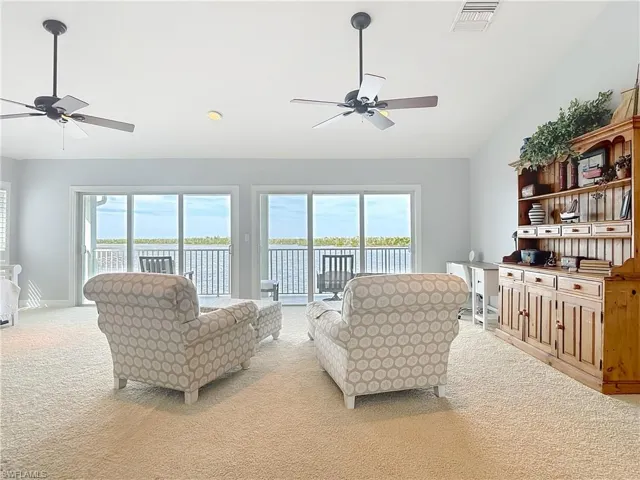 Living area with a ceiling fan, light colored carpet, a water view, vaulted ceiling, and recessed lighting