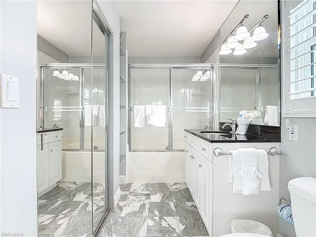 Bathroom with vanity, combined bath / shower with glass door, and light marble finish floors