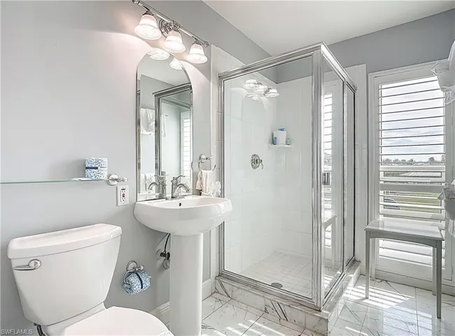 Bathroom with plenty of natural light, marble finish floors, and a shower stall