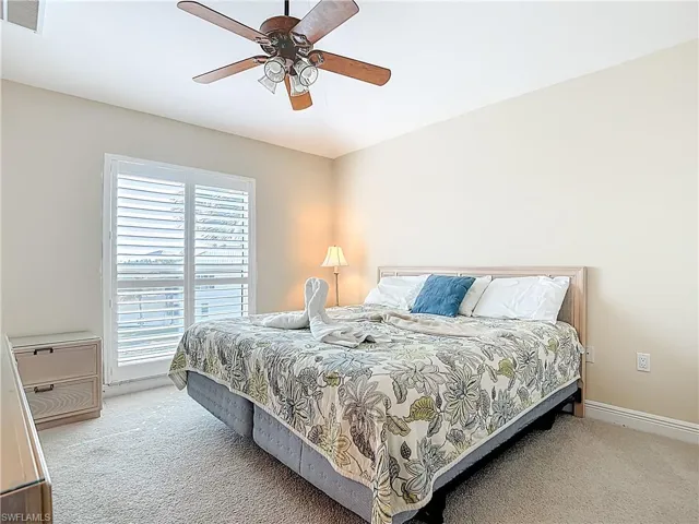 Carpeted bedroom with a ceiling fan and baseboards