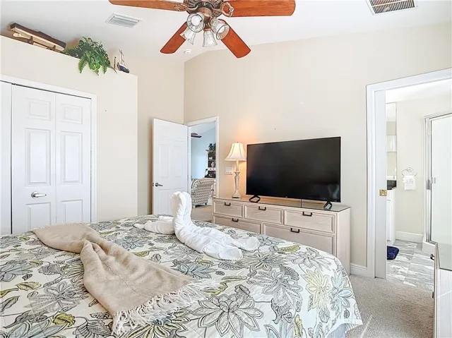 Bedroom featuring light colored carpet, a closet, and ceiling fan