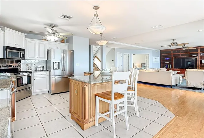 Kitchen with ceiling fan, appliances with stainless steel finishes, a breakfast bar, tasteful backsplash, and open floor plan