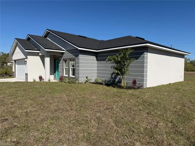 View of front of property with a front lawn, a garage, driveway, and roof with shingles
