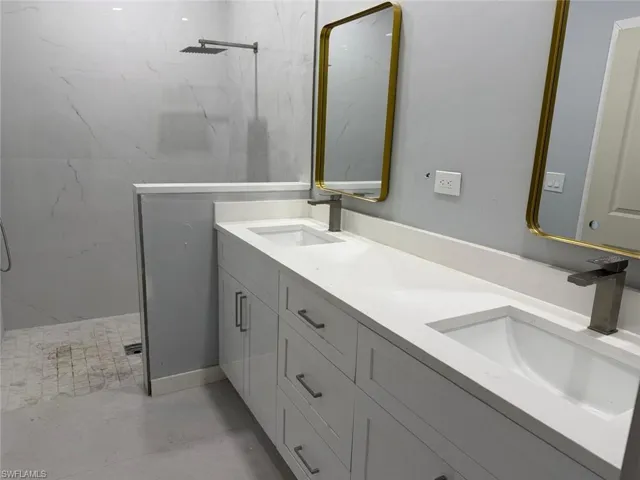 Bathroom with double vanity and a marble finish shower