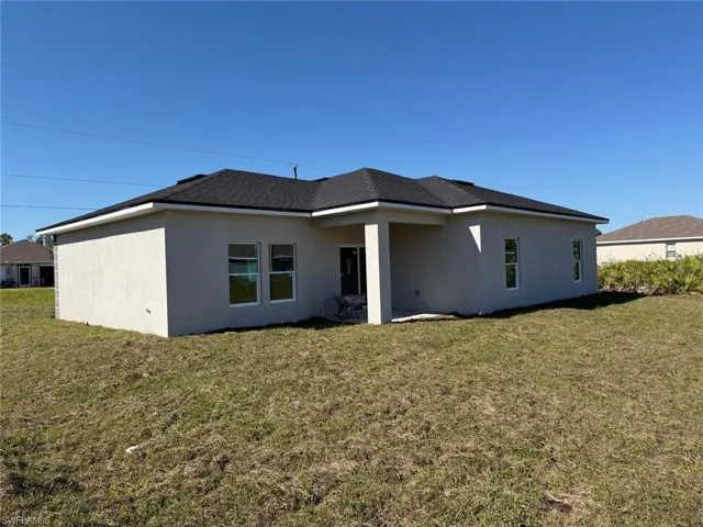 Back of house featuring stucco siding, a yard, and a patio