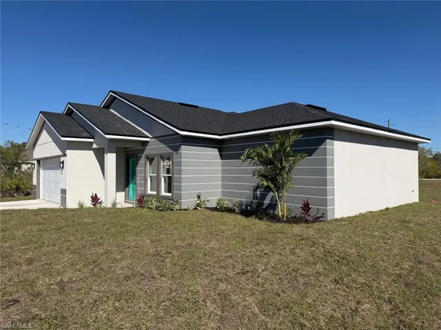 View of side of home featuring a yard, an attached garage, roof with shingles, and stucco siding