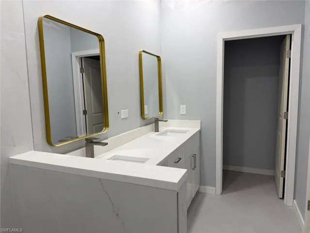 Bathroom with double vanity and finished concrete flooring