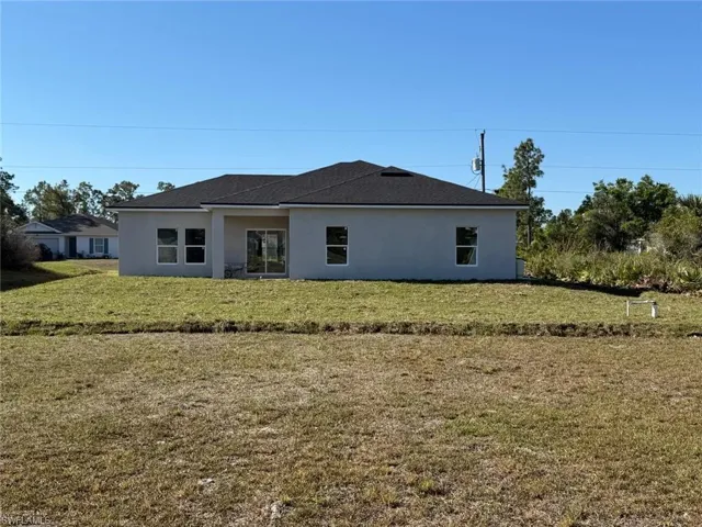 Rear view of property with stucco siding and a lawn