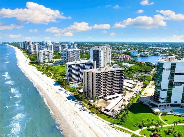 Birds eye view of property with a water view, a beach view, and a city view