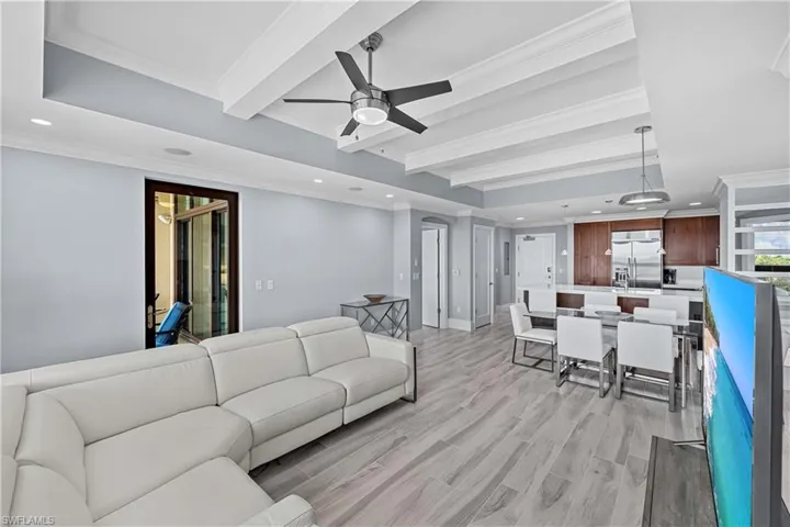 Living room with ceiling fan, beam ceiling, crown molding, and light hardwood / wood-style flooring