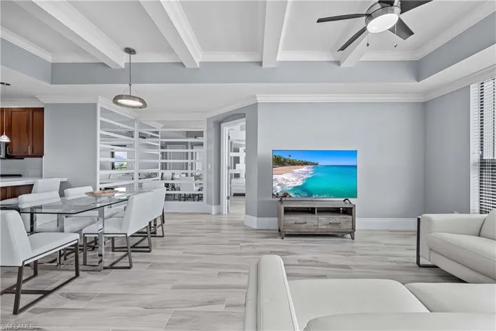 Living room with ceiling fan, ornamental molding, beamed ceiling, and light wood-type flooring
