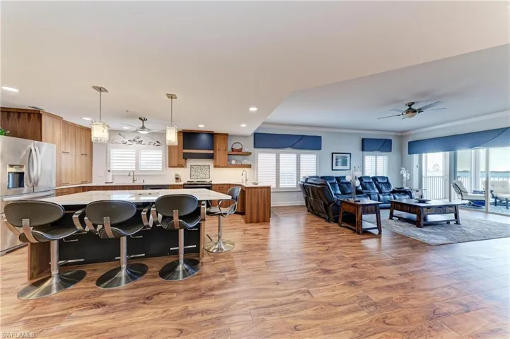 Kitchen with a ceiling fan, stainless steel fridge with ice dispenser, a kitchen breakfast bar, pendant lighting, and crown molding