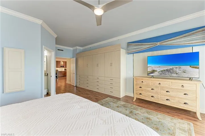 Bedroom featuring a closet, dark wood-style flooring, ornamental molding, and ceiling fan