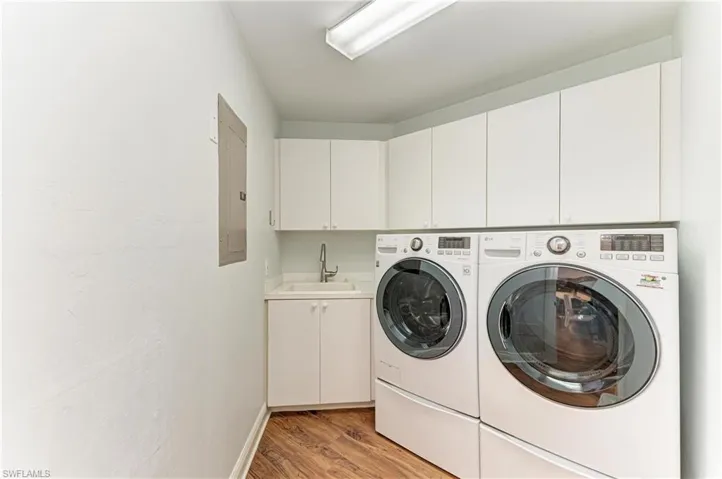 Laundry area with washing machine and clothes dryer, cabinet space, light wood-style floors, and electric panel