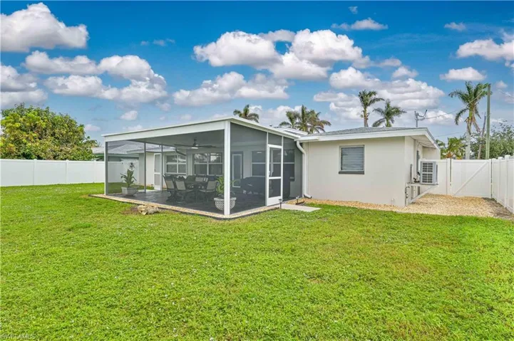 Rear view of property with a screened lanai, ceiling fan, a yard, and a patio area