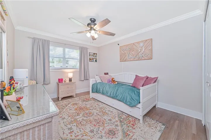 Bedroom featuring ceiling fan, wood-type flooring, and ornamental molding