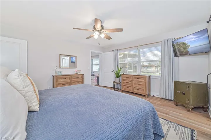 Bedroom with ceiling fan, multiple windows, and light wood-type flooring