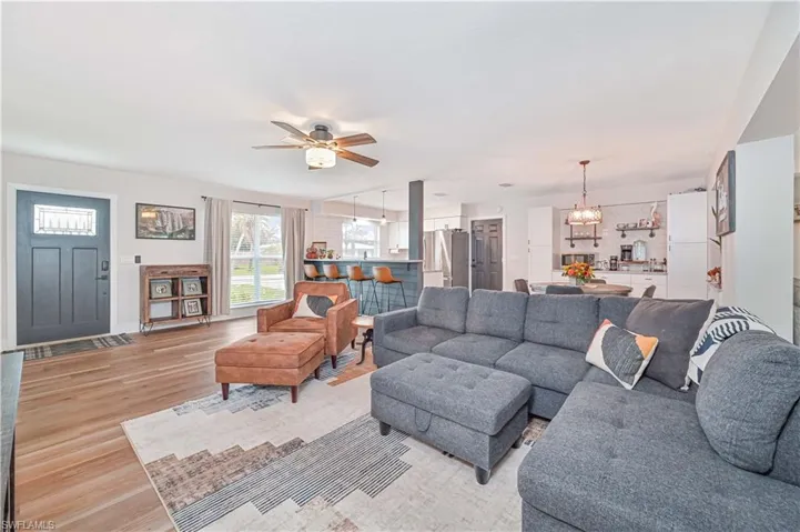 Living room featuring ceiling fan with notable chandelier and light hardwood / wood-style flooring