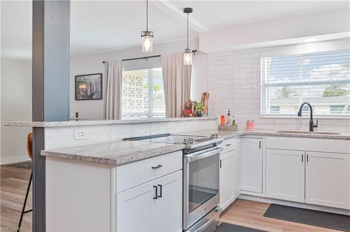 Kitchen featuring white cabinets, decorative backsplash, stainless steel range with electric stovetop, and sink
