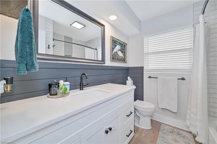 Full bathroom featuring wood-type flooring, vanity, toilet, and shower / tub combo with curtain