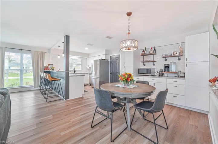 Dining space with plenty of natural light, a notable chandelier, light hardwood / wood-style floors, and sink
