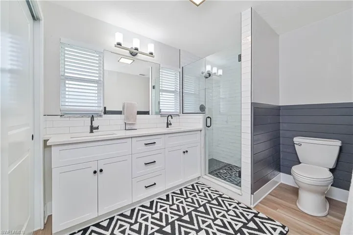 Bathroom with wood-type flooring, vanity, toilet, and a shower with shower door