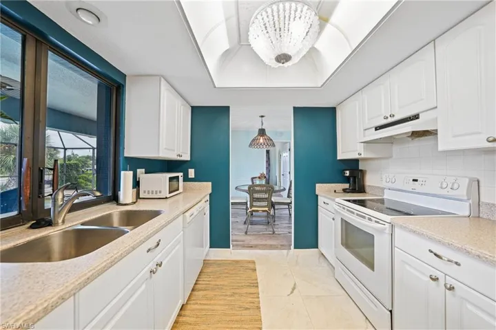 Kitchen featuring white appliances, a chandelier, and white cabinets