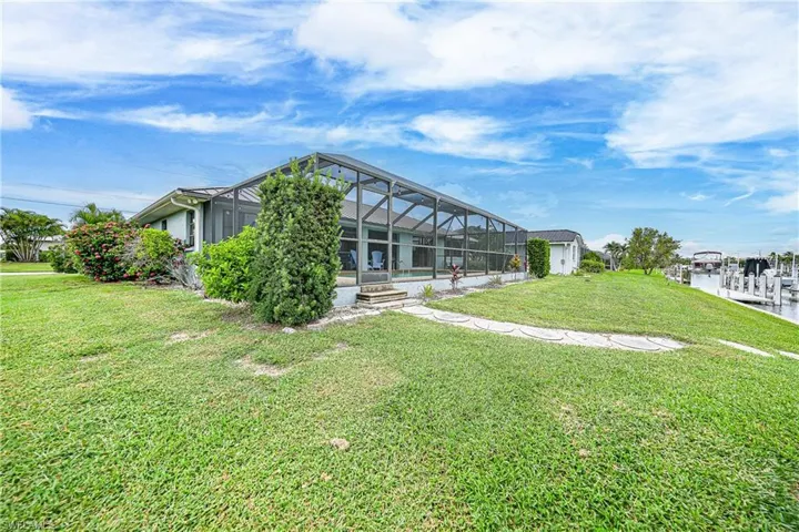 Rear view of property with a sunroom, glass enclosure, a yard, and a water view