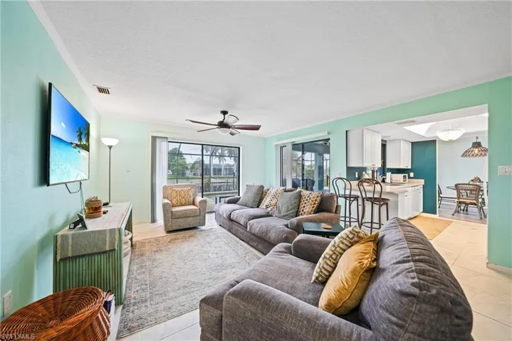 Living room with ceiling fan, a textured ceiling, and light tile patterned flooring