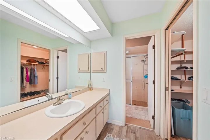 Bathroom with a walk in closet, a stall shower, vanity, and light wood-style floors