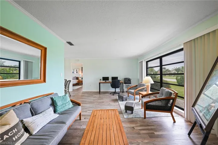 Living area with hardwood / wood-style flooring, a textured ceiling, an office area, and crown molding