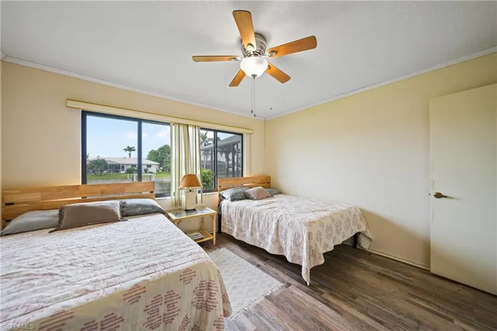 Bedroom with crown molding, dark wood-style flooring, and a ceiling fan