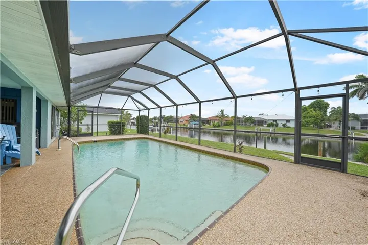 Swimming pool with a sunroom, a water view, glass enclosure, and a residential view