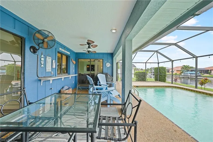 Swimming pool featuring a sunroom, a patio area, a ceiling fan, outdoor dining area, and glass enclosure